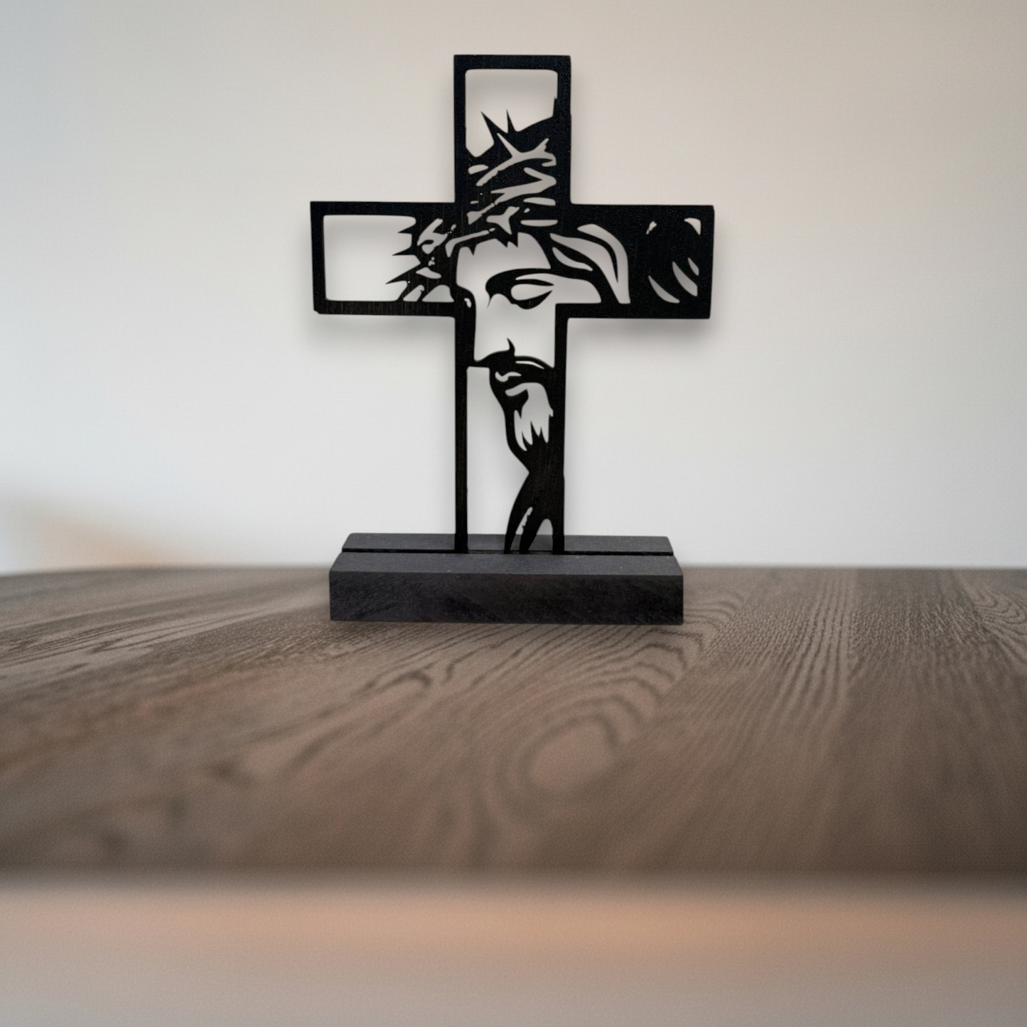Staand houten kruis met uitgesneden silhouet van Jezus in zwarte MDF houder op houten tafel